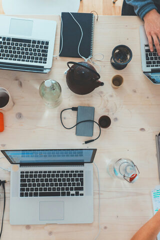 overhead view of large desk with multiple laptops - circular economy in tech