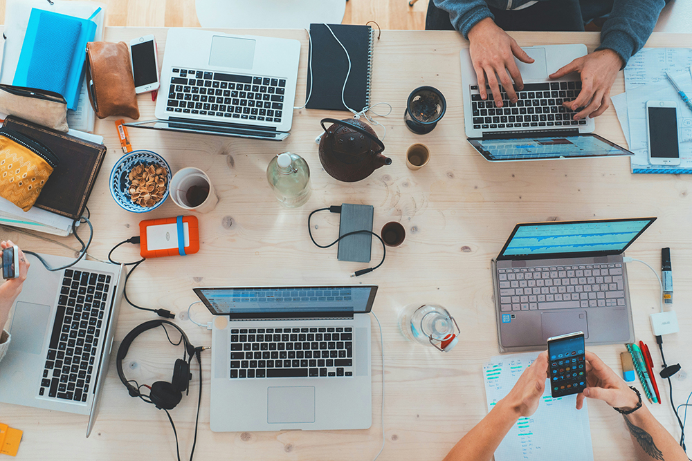 overhead view of large desk with multiple laptops - circular economy in tech